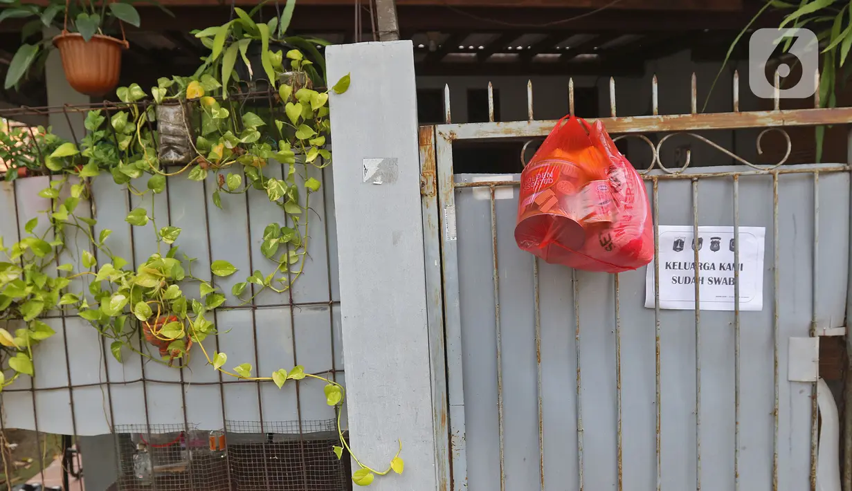 Bantuan bahan pokok kepada pasien positif Covid-19 yang melakukan isolasi mandiri di rumahnya terlihat di pagar di RT03/RW03, Kelurahan Cilangkap, Jakarta, Jumat (21/5/2021). (Liputan6.com/Herman Zakharia)