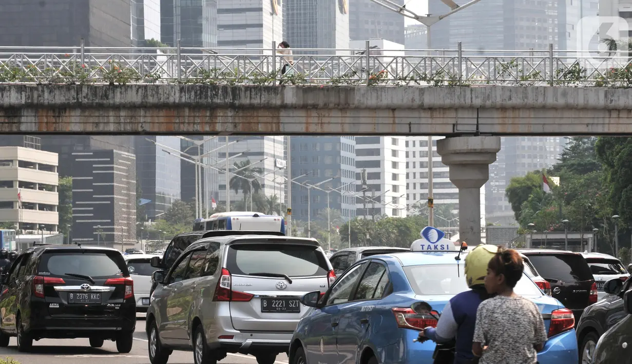 Kendaraan melintas di bawah jembatan penyeberangan orang (JPO) yang tidak beratap di jalan Sudirman, Jakarta,  Rabu (6/11/2019). Pemprov DKI melalui Dinas Bina Marga mencopot atap JPO Sudirman agar pejalan kaki dapat menikmati pemandangan gedung-gedung pencakar langit. (merdeka.com/Iqbal Nugroho)