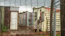 Seorang perempuan yang tinggal di pemukiman informal Vlakfontein menutup jendelanya saat hujan badai di luar Johannesburg, Senin (13/12/2021). Rata-rata kasus baru COVID-19 harian di Afrika Selatan telah meningkat selama dua minggu terakhir. (AP Photo/Jerome Delay)