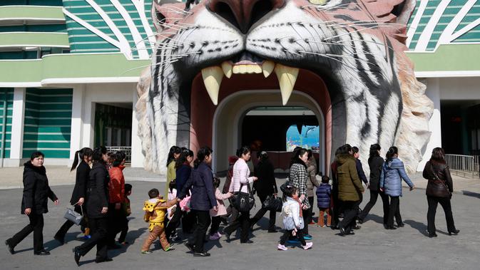 Sejumlah wanita berjalan melewati gerbang Kebun Binatang Pusat Korea saat perayaan Hari Perempuan Internasional di Pyongyang, Korea Utara, Jumat (8/3). (AP Photo/Dita Alangkara)