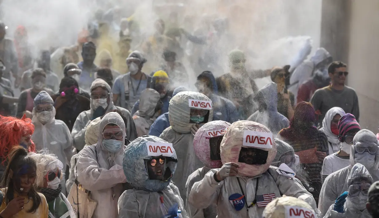 Orang-orang berkostum astronot NASA dalam perang tepung selama perayaan 'Ash Monday' di pelabuhan Galaxidi, Yunani, 11 Maret 2019. Pesta itu sebagai pertanda akhir musim karnaval dan awal periode hari Prapaskah sampai Paskah Ortodoks. (ARIS MESSINIS/AFP)