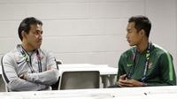 Pelatih Timnas Indonesia, Bima Sakti, berbincang dengan Hansamu Yama, saat jumpa pers jelang laga Piala AFF 2018 di Stadion Nasional, Singapura, Kamis (8/11). Timnas akan berhadapan dengan Singapura. (Bola.com/M. Iqbal Ichsan)
