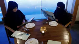 Dua wanita berhijab memilih menu di sebuah kafe di Riyadh, Arab Saudi (6/10). (REUTERS/Faisal Al Nasser)