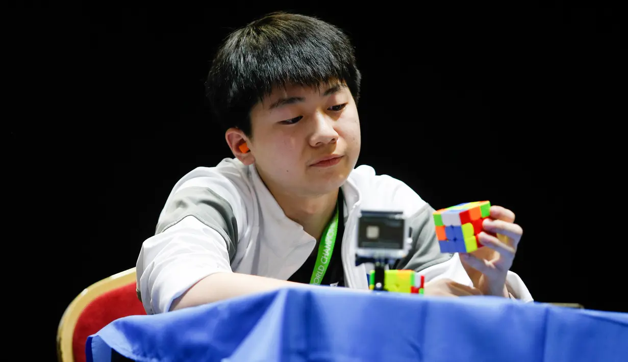 Seorang peserta memerhatikan rubiknya saat mengikuti kejuaraan kubus Rubik Dunia di Saint Denis, Paris, Prancis (16/7). (AFP Photo/Geoffroy Van Der Hasselt)