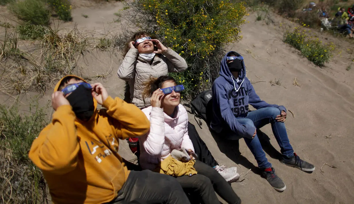 Orang-orang menyaksikan gerhana matahari total di Piedra del Aguila, Argentina, Senin (14/12/2020). Gerhana matahari total terlihat dari wilayah Patagonia utara Argentina dan dari Araucania di Chili. (AP Photo/Natacha Pisarenko)