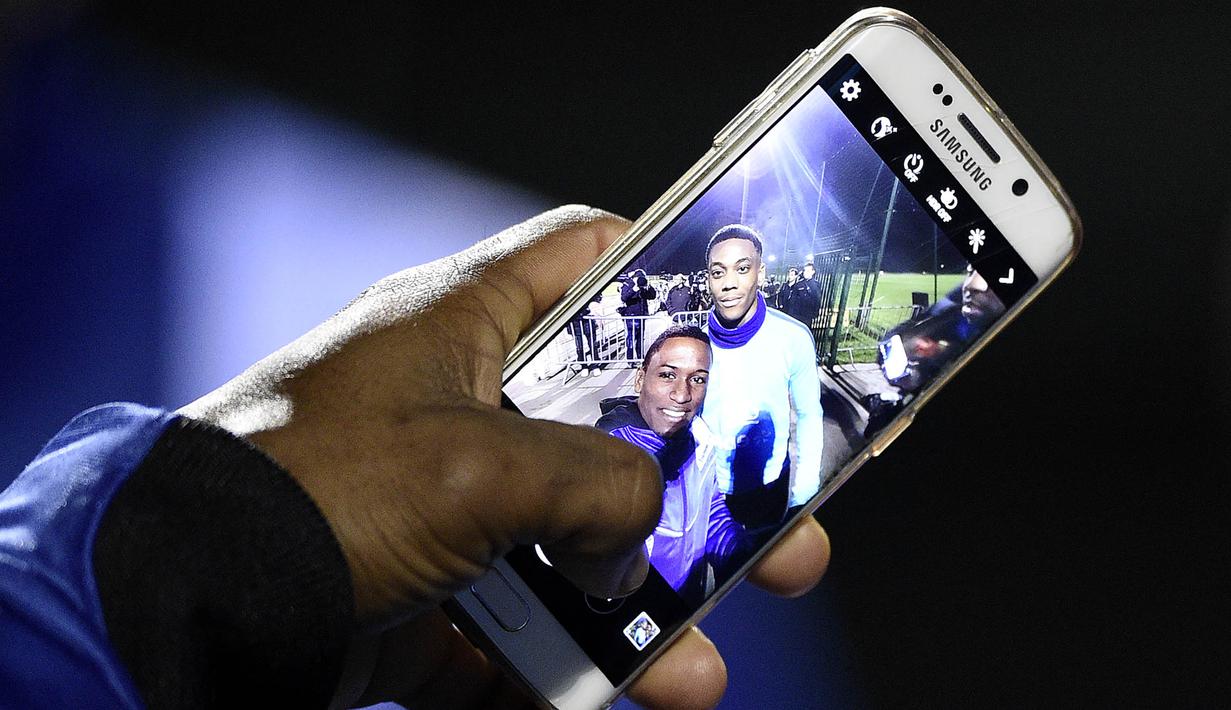Fans menunjukan foto selfie bersama penyerang MU dan juga timnas Prancis, Anthony Martial usai menonton latihan skuat Les Blues jelang laga persahabatan melawan Jerman di Yvelines, Prancis, Selasa (10/11/2015). (AFP Photo/Franck Fife)
