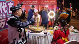Warga menyaksikan para petani yang mengenakan kostum etnis Qiang menjual produk lokal melalui siaran langsung daring (livestream) di Beichuan, Provinsi Sichuan, China, 14 November 2020. Sekitar 17.000 pesanan senilai dua juta yuan diperoleh dalam livestream berdurasi dua jam. (Xinhua/Jiang Hongjing)