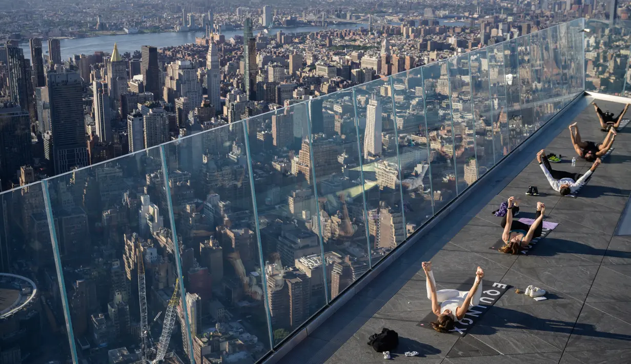 Praktisi yoga menghadiri kelas di Edge Observation Deck, Manhattan, New York, Amerika Serikat, Kamis (17/6/2021). Edge Observation Deck disebut sebagai 'dek langit luar ruang tertinggi di Belahan Barat'. (Ed JONES/AFP)
