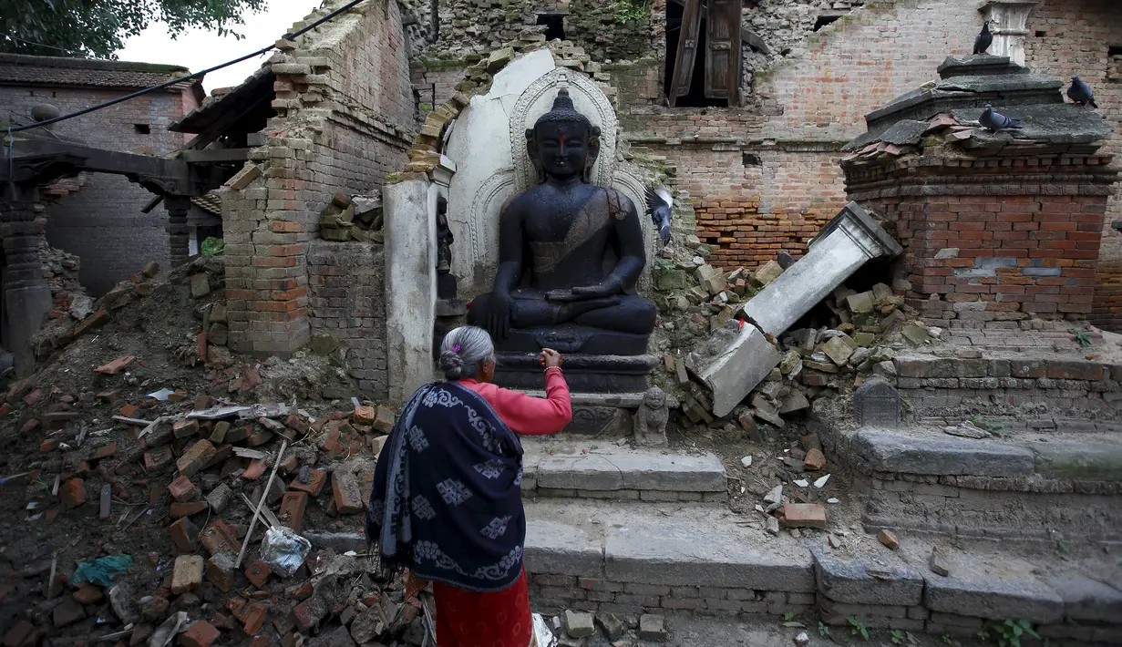 Seorang warga berdoa di patung Buddha yang rusak akibat gempa di Bhaktapur, Nepal (14/7/2015). PBB melaporkan dua bulan setelah gempa di Nepal, warga masih sulit mendapatkan makanan dan perawatan kesehatan. (REUTERS/Navesh Chitrakar)