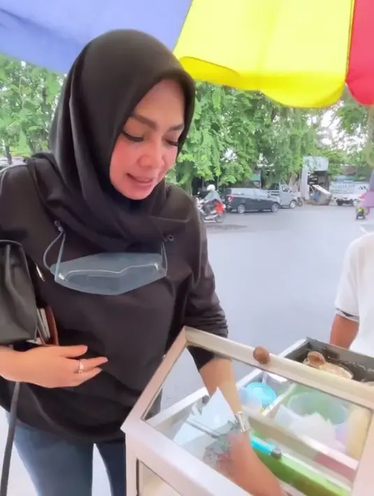 Momen Rieta Amilia jajan leker di Surabaya ini terabadikan kamera. Ia terlihat antusias melihat-lihat leker di dagangan si penjual. Kesukaan Rieta dengan jajanan pinggir jalan ini terlihat jelas dari raut wajahnya. (Liputan6.com/IG/rieta_amilia)