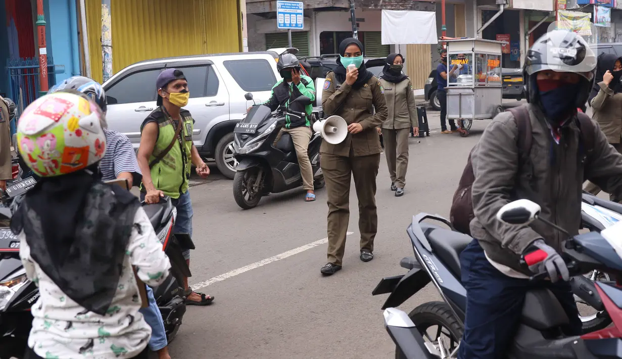 Petugas Satpol PP mengimbau warga untuk menggunakan masker dan menjaga jarak di Pasar Lama, Kota Tangerang, Banten, Sabtu (9/6/2020). Pemkot Tangerang melakukan penegasan pada PSBB tahap dua dengan menugaskan petugas di keramaian guna memutus rantai penyebaran COVID-19.  (Liputan6.com/Angga Yuniar)