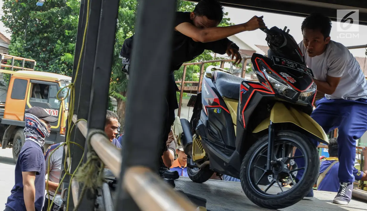 Petugas menaikkan sepeda motor milik peserta program mudik gratis dari Pemprov DKI Jakarta ke atas truk sebelum diberangkatkan di Terminal Pulogadung, Rabu (29/5/2019). Sebanyak 712 motor akan di kirim ke 10 kota tujuan pada tahap pertama Mudik Gratis Pemprov DKI 2019. (Liputan6.com/Faizal Fanani)