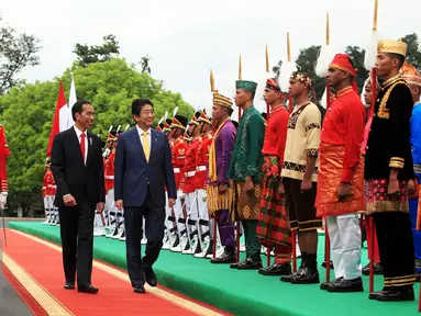 Presiden Joko Widodo berjalan bersama Perdana Menteri Jepang, Shinzo Abe saat menyambut kedatangannya di Istana Kepresidenan Bogor, Jawa Barat, Minggu (15/1). (Liputan6.com/Panca Syurkani/Pool)