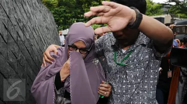 Istri Hakim MK Patrialis Akbar, Sufriyeni (kiri) menutup wajah saat menuju ruang tahanan KPK, Jakarta, Senin (30/1). Patrialis Akbar menjadi tersangka dugaan penerima suap uji materi UU peternakan dan Kesehatan Hewan. (Liputan6.com/Helmi Fithriansyah)