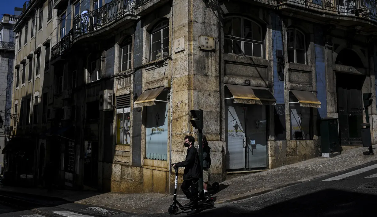 Seorang turis mengendarai skuter di Lisbon saat pemerintah melonggarkan pembatasan virus corona, Senin (5/4/2021). Portugal membuka kembali museum, teras kafe, taman dan sekolah menengah hampir dua bulan setelah pengetatan pembatasan COVID-19. (PATRICIA DE MELO MOREIRA/AFP)