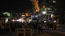 Sejumlah penumpang berpose di depan kereta wisata yang dihiasi lampu Natal di Bogota (20/12/2019). Meyambut Hari Natal, kereta wisata di Kolombia membuat cara unik dengan memasangkan lampu warna-warni agar menjadi daya tarik penumpang. (AFP Photo/Juan Barreto)