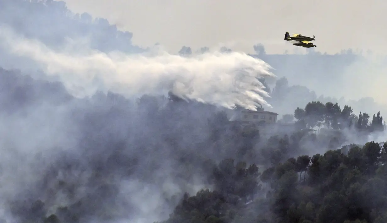 Pesawat pemadam kebakaran menjatuhkan air ke atas kebakaran hutan di dekat Betxi, sekitar 60 kilometer utara Valencia, Spanyol, Senin, 27 Juli 2026. (AFP/ Jose Jordan)