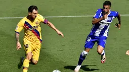 Pemain Barcelona Lionel Messi (kiri) berebut bola dengan pemain Alaves Victor Camarasa pada pertandingan La Liga di Stadion Mendizorroza, Vitoria, Spanyol, Minggu (19/7/2020). Barcelona menang 5-0. (AP Photo/Alvaro Barrientos)