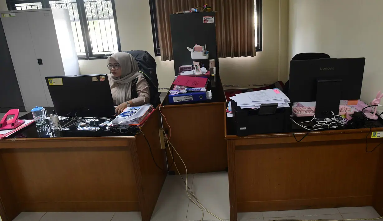 Masing-masing instansi dipersilakan mengatur sistem serta pola kerja dengan dukungan teknologi agar produktivitas tidak terganggu. Tampak dalam foto, pegawai bekerja di depan komputer dengan beberapa meja kursi yang kosong saat penerapan Work From Home (WFH) bagi Aparatur Sipil Negara (ASN) di kantor Kecamatan Limo, Depok, Jawa Barat, Jumat (10/4/2026). (merdeka.com/Arie Basuki)