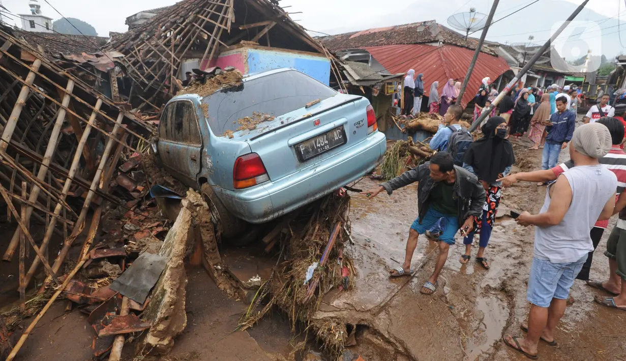 Warga menyaksikan mobil yang rusak usai banjir bandang melanda Kampung Cibuntu, Desa Pasawahan, Kecamatan Cicurug, Sukabumi, Jawa Barat, Selasa (22/9/2020). Data sementara puluhan bangunan rusak berat, 12 rumah hanyut, dan dua korban hilang masih dicari. (merdeka.com/Arie Basuki)