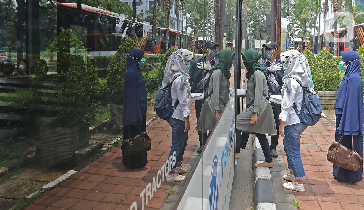 Petugas medis menaiki bus Transjakarta sebagai moda jemput-antar di Hotel Grand Cempaka, Jakarta, Sabtu (28/3/2020). Pemprov DKI menyediakan tempat tinggal dan transportasi untuk tenaga medis dan kesehatan yang menangani pandemi virus corona atau COVID-19. (Liputan6.com/Herman Zakharia)