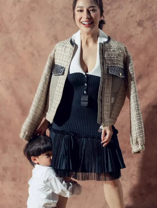 Dress tanpa lengan tersebut dibalut jaket rajut berkantung dalam warna beige dan hitam [@nikitawillyofficial94]