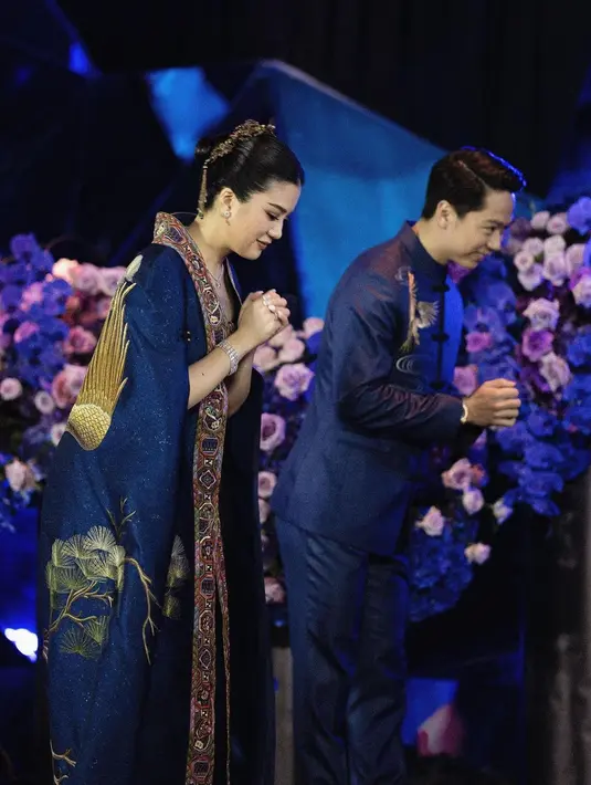 Tak kalah memesona dan megah, Valencia dan Kevin memilih mengenakan cheongsam untuk acara resepsi pernikahan mereka di Jakarta. Cheongsam biru navy yang super cantik dihiasi motif burung dan bunga sakura yang menarik. Foto: Instagram.