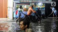 Pengendara sepeda motor mendorong kendaraannya saat melewati banjir di Jalan Ciracas Raya, Jakarta, Jumat (12/8/2022). Hujan lebat yang terjadi sore tadi membuat Jalan Ciracas Raya tergenang air dan kendaraan terjebak banjir. (Liputan6.com/Faizal Fanani)