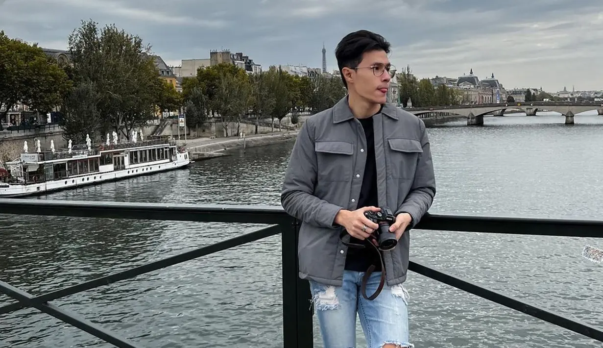 Kenakan jaket warna abu dengan ripped jeans, gaya berpakaian pemeran Agil di sinetron Love Story The Series ini membuatnya makin keren. Pose candid sembari memegang kamera, pesona Emer ini bikin klepek-klepek. Pemandangan Paris yang indah membuat hasil akhir foto Emer jadi makin menarik. (Liputan6.com/IG/@emeraldyrafael)