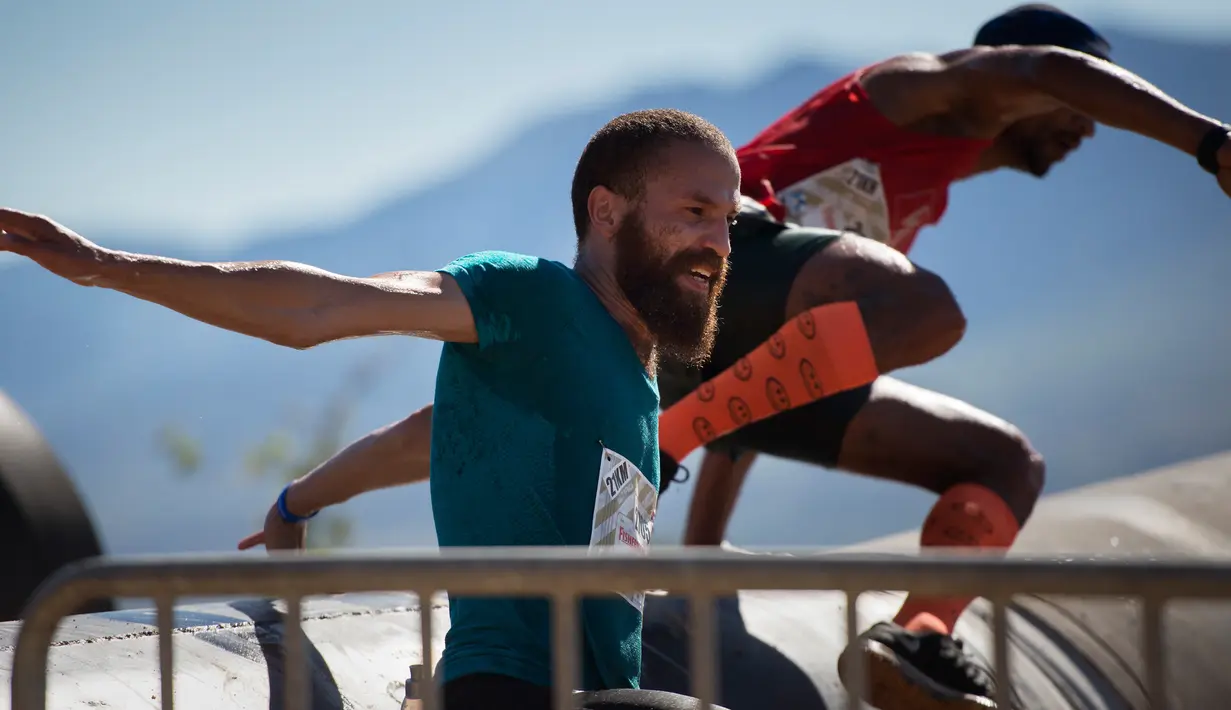 Peserta melompati pipa besar selama lomba lari Strongman Run di kota Paarl, Afrika Selatan, 13 Oktober 2018. Strongman Run pertama kali digelar di Munster, Jerman pada 2007 silam dan hanya diikuti prajurit militer. (RODGER BOSCH/AFP)