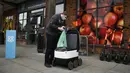 Pekerja toko Co-op memuat tas ke dalam robot otonom bernama Starship saat mengirimkan bahan makanan di Milton Keynes, Inggris, 20 September 2021. Robot Starship bertugas mengantarkan belanja dan makanan. (DANIEL LEAL-OLIVAS/AFP)