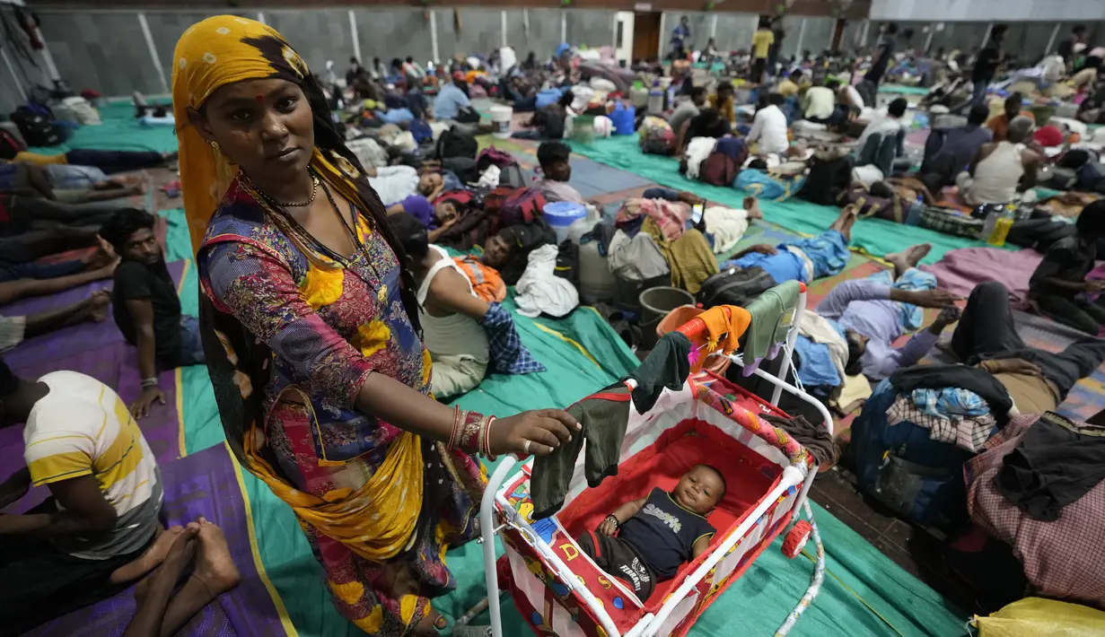 Seorang wanita berdiri di samping seorang anak, keduanya dievakuasi dari pelabuhan Kandla menjelang Topan Biparjoy, di tempat penampungan di Gandhidham, India, Selasa, 13 Juni 2023. (AP Photo/Ajit Solanki)