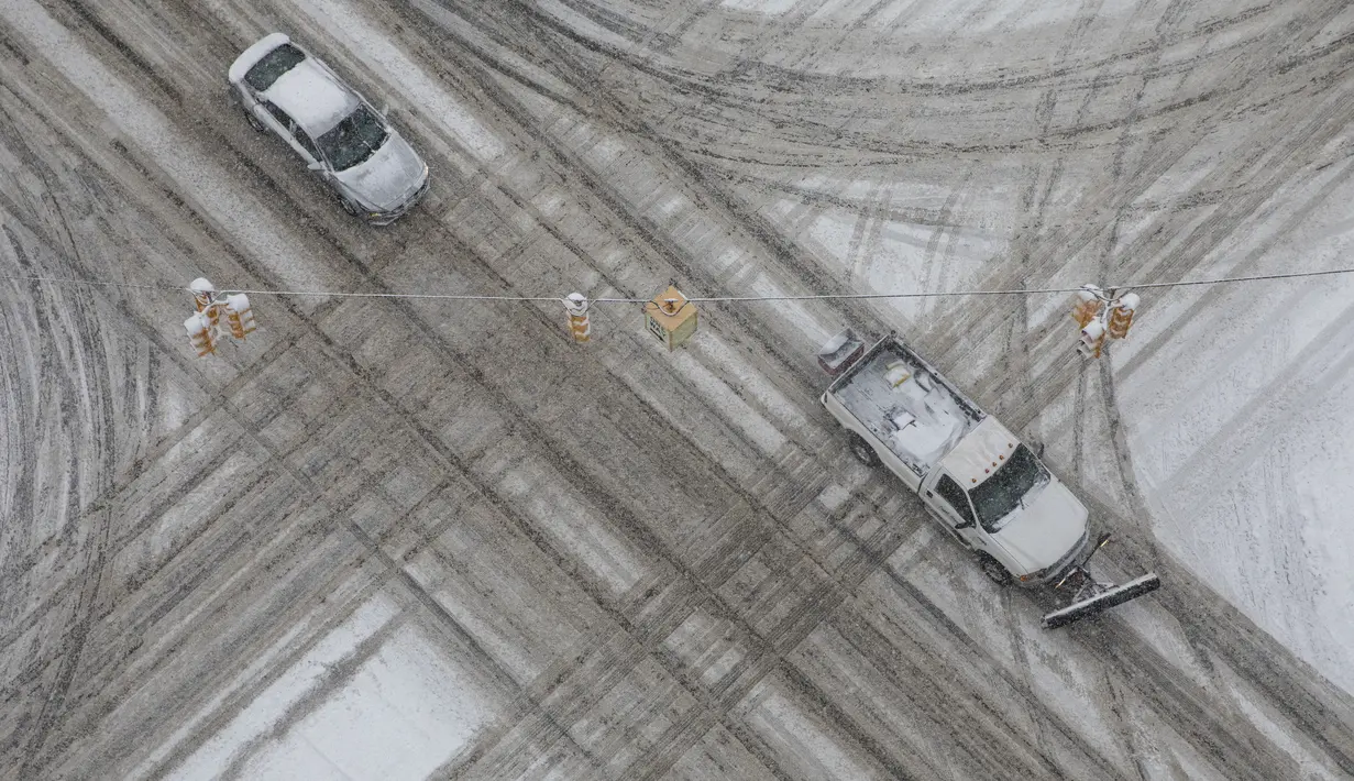 Kendaraan melewati persimpangan Rose Street dan West Michigan Avenue selama badai salju di pusat kota Kalamazoo, Michigan, Rabu (2/2/2022). Badai salju membuat maskapai membatalkan ratusan penerbangan. (Joel Bissell/Kalamazoo Gazette via AP)