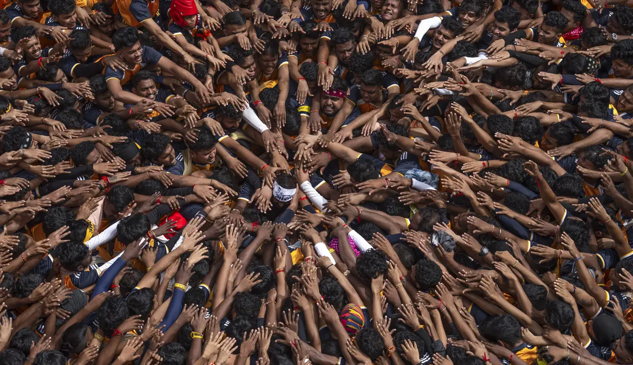 Orang-orang memberikan penghormatan sebelum membentuk piramida manusia untuk mencapai pot tanah yang menjorok  saat merayakan festival Hindu Janmashtami, festival yang menandai kelahiran Dewa Hindu Krishna, di Mumbai, India, Selasa, 27 Agustus 2024. (AP Photo/Rafiq Maqbool)