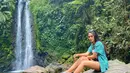 Garneta Haruni nampak santai dengan kemeja biru dan sepatu slip on. Ia nampak sedang menikmati liburannya di sebuah air terjun di daerah Jawa Barat. (Liputan6.com/IG/@garnetaharuni).