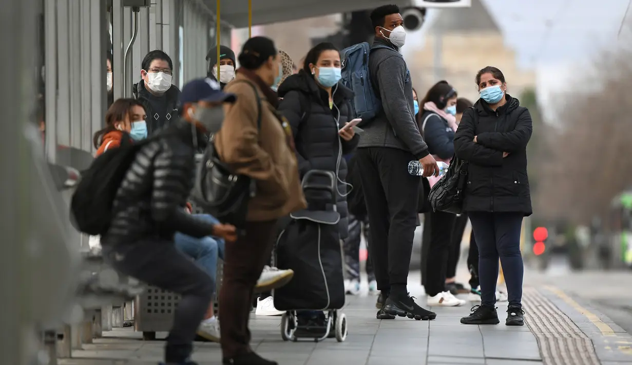 Orang-orang menunggu trem di Stasiun Flinders Street pada hari pertama wajib masker di tempat umum, di Melbourne, Kamis (23/7/2020). Penduduk kota terpadat kedua di Australia, Melbourne, diwajibkan mengenakan masker ketika meninggalkan rumah untuk mencegah penyebaran COVID-19. (William WEST/AFP)