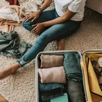 Ilustrasi packing baju, koper. (Foto oleh Vlada Karpovich: https://www.pexels.com/id-id/foto/orang-wanita-duduk-sepatu-7365311/)
