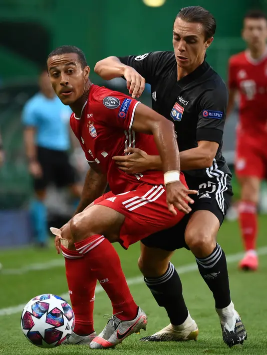 Gelandang Bayern Munchen, Thiago berusaha membawa bola dari kawalan gelandang Lyon, Maxence Caqueret pada pertandingan Semifinal Liga Champions di stadion Jose Alvalade di Lisbon, Portugal, Rabu, (19/8/2020). Munchen menang telak 3-0 dan melaju ke Final. (Franck Fife/Pool via AP)