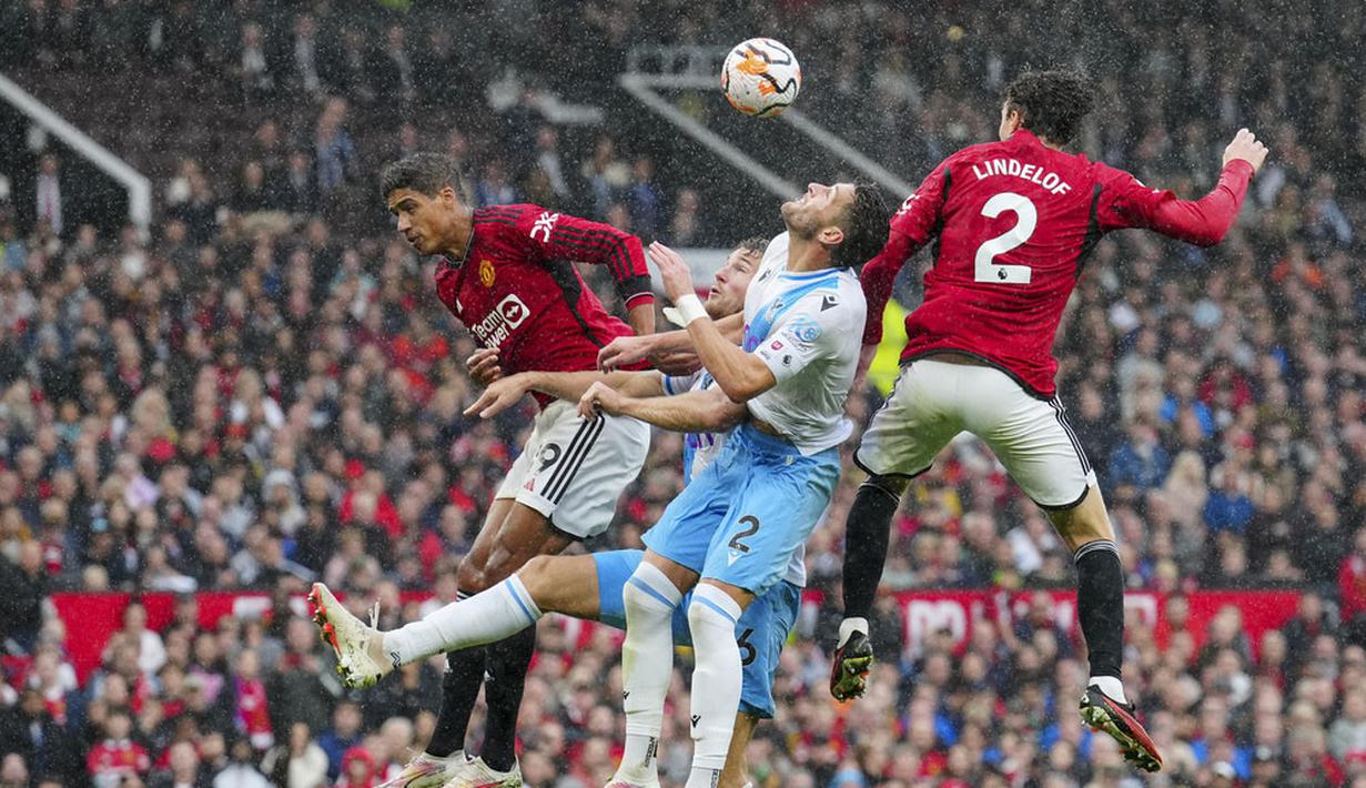 Pemain Crystal Palace, Joel Ward, duel udara dengan pemain Manchester United, Victor Lindelof dan Raphael Varane pada laga Liga Inggris di Stadion Old Trafford, Minggu (1/10/2023). Kekalahan ini membuat MU tertahan di peringkat 10 klasemen sementara EPL, sementara Crystal Palace naik ke peringkat sembilan. (AP Photo/Jon Super)