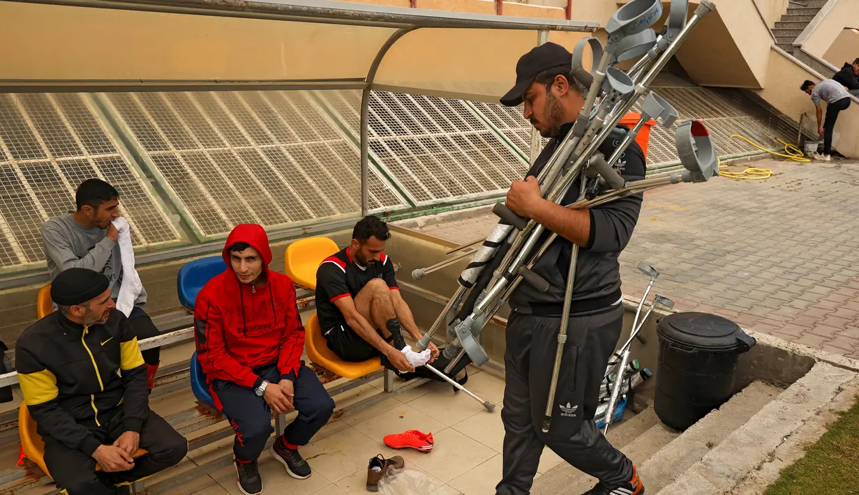 Seorang ofisial tim menyiapkan kruk menjelang pertandingan final kejuaraan lokal sepak bola korban amputasi antara Al-Jazeera melawan Al-Abtal yang diselenggarakan oleh Komite Palang Merah Internasional (ICRC), di tengah pandemi COVID-19, di Kota Gaza, (18/3/2021). (AFP/Mohammed Abed)