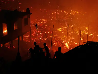 Warga berusaha memadamkan api dengan air saat kebakaran di lingkungan Educandos, di Manaus, Brasil (17/12). Para pihak berwenang mengatakan setidaknya 600 rumah kayu hanggus terbakar. (AP Photo/Edmar Barros)