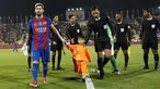 Bintang Barcelona Lionel Messi menggandeng bocah Afghanistan, Murtaza Ahmadi jelang laga melawan Al Ahli di Doha, Qatar, Selasa (13/12). Murtaza menjadi sensasi di internet karena mengenakan plastik dengan nomor punggung 10 untuk Messi. (Karim Jaafar/AFP)