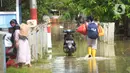Warga melintasi banjir di Desa Karangligar dan Dusun Pengasinan kecamatan Teluk Jambe Barat, Kabupaten Karawang, Selasa (6/12/2022).  Banjir yang terjadi setelah hujan deras yang mengguyur sejak Minggu (4/12/2022) mulai berangsur surut. (merdeka.com/Imam Buhori)