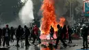 Api menyala di dekat demonstran setelah terjadi bentrokan saat peringatan Hari Buruh di Santiago, Chili (1/5). Hari buruh tahunan ini berawal dari usaha gerakan serikat buruh untuk merayakan keberhasilan ekonomi dan sosial para buruh. (AFP/Claudio Reyes)