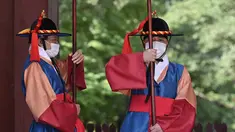 Anggota 'penjaga istana' yang mengenakan masker berdiri untuk turis di gerbang utama Istana Deoksugung di Seoul (4/9/2020). Korea Selatan melaporkan 198 kasus Covid-19 baru pada 4 September, hari ke-22 berturut-turut meningkat tiga digit. (AFP/Jung Yeon-je)