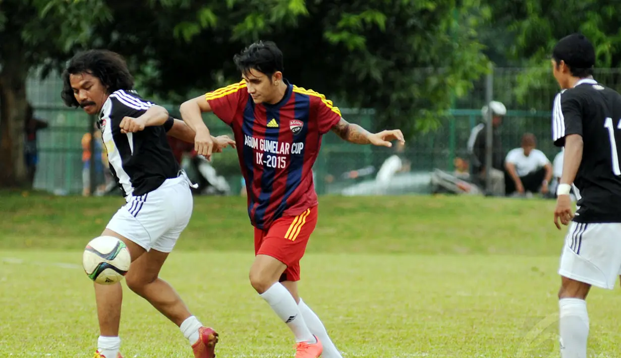 Pemain Paski-Man FC, Ajul Jiung (kiri) berebut bola dengan Vicky Nitinegoro (Selebriti FC) saat berlaga di turnamen Agum Gumelar Cup di Lapangan C Senayan, Jakarta (9/1/2015). Paski-Man FC unggul 1-0 atas Selebrity FC. (Liputan6.com/Helmi Fithriansyah