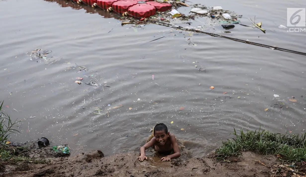Anak-anak berjalan di tumpukan sampah di kawasan Banjir Kanal Barat, Petamburan, Jakarta, Jumat (9/11). Mendung yang menyelimuti ibukota Jakarta, tidak menyurutkan anak-anak bermain di Sungai Banjir Kanal Barat. (Liputan6.com/Fery Pradolo)