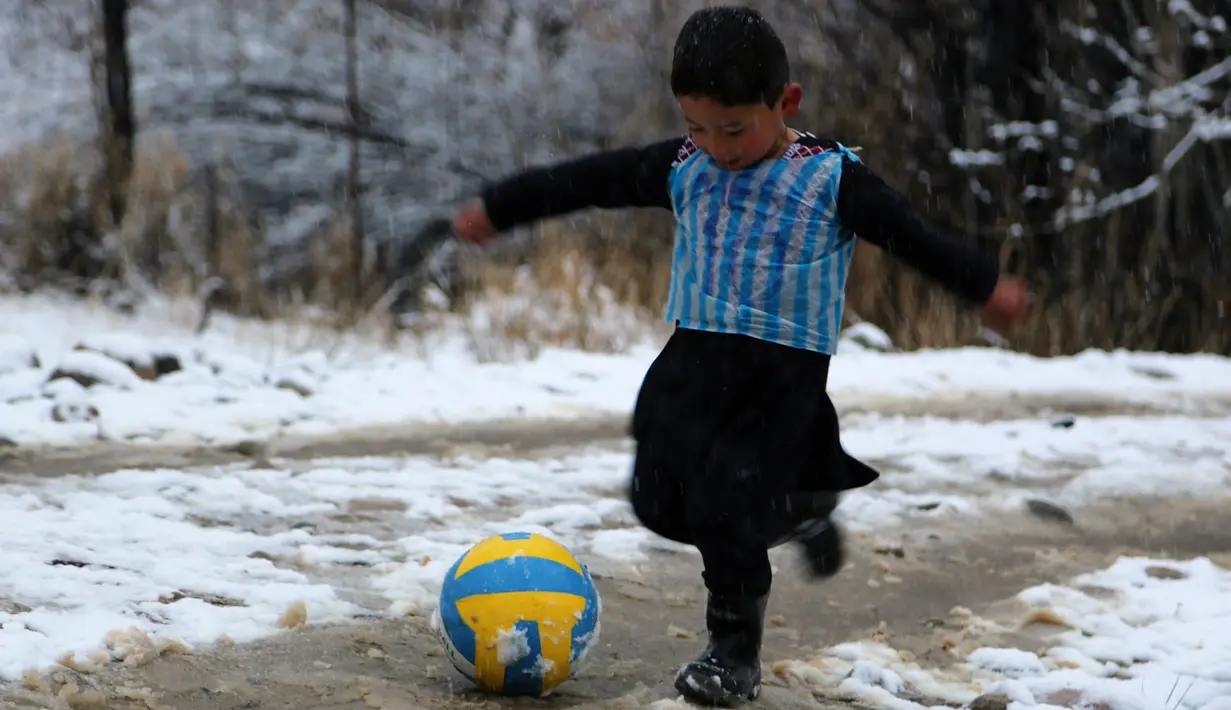 Seorang anak laki-laki Afghanistan, Murtaza Ahmadi berkaos kantong kresek timnas Argentina milik Lionel Messi terlihat bermain bola di  kabupaten Jaghori, provinsi Ghazni, 29 Januari 2016. Sebelumnya, foto Murtaza itu menyebar luas di dunia maya (STR/AFP)