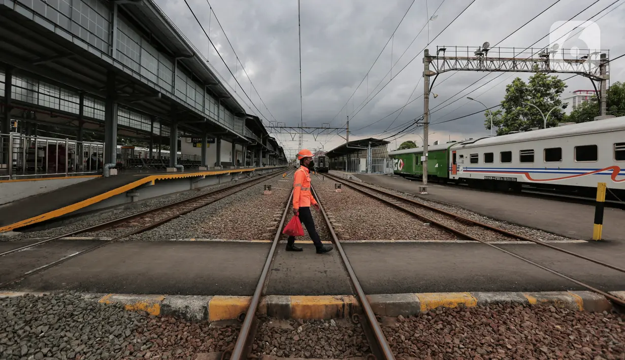 Petugas berjalan menyeberangi rel di Stasiun Pasar Senen, Jumat (24/4/2020). Terkait larangan mudik Lebaran 2020, Stasiun Pasar Senen untuk sementara tidak melayani keberangkatan kereta jarak jauh dari tanggal 24 sampai 30 April 2020 mendatang. (Liputan6.com/Johan Tallo)