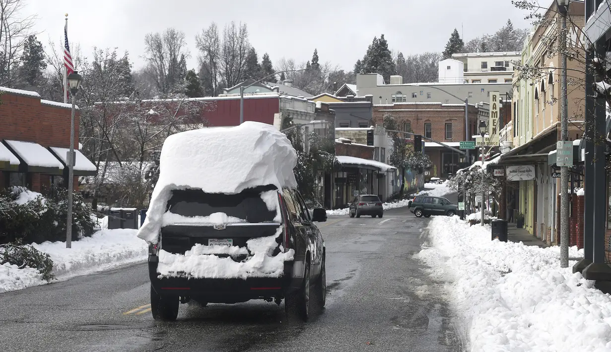 Anggota masyarakat mulai mengendarai kendaraan mereka dan turun ke jalan di Grass Valley, California, Selasa (28/12/2021). Ribuan masih belum mendapatkan listrik di Nevada County imbas salju menutupi kediaman mereka. (Elias Funez/The Union via AP)